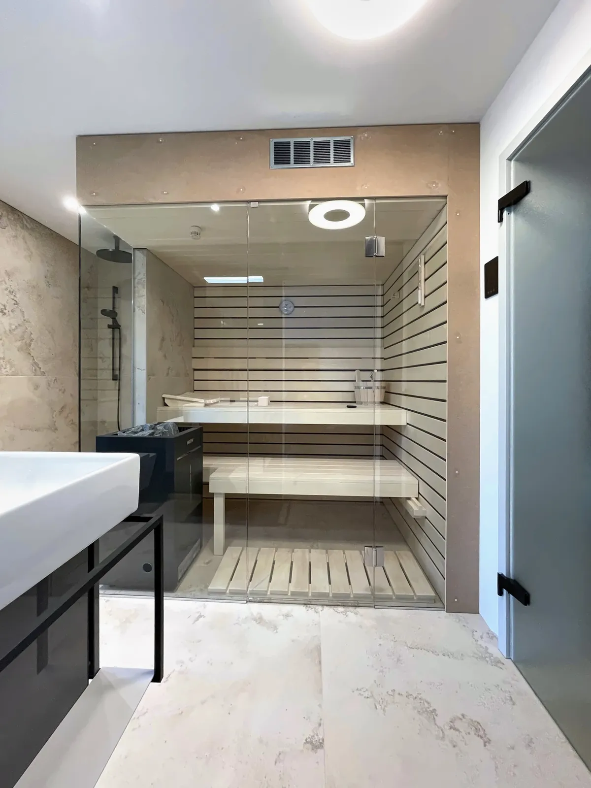Umgebautes Bad mit Sauna hinter Glas und Keramik in Steinoptik