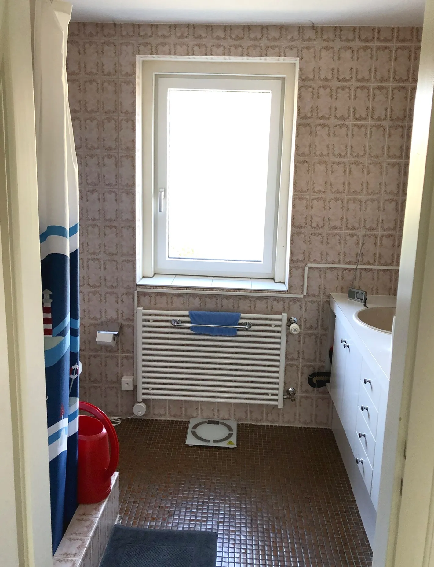 Vorher: die enge Nasszelle mit Blümchenplatten und dunklem Mosaikboden